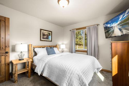 a bedroom with a white bed and a window at Glacier River Ranch - Middle Fork in Columbia Falls