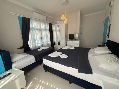 a hotel room with two beds and a television at Olivento Pansiyon in Ayvalık