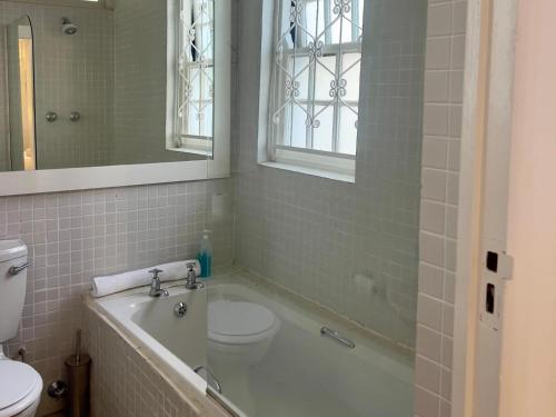 a bathroom with a tub and a toilet and a sink at Nomad City Suites in Cape Town