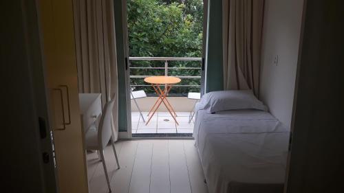a bedroom with a bed and a balcony with a table at Balkony 407 - Três quartos Perto UNB in Brasilia