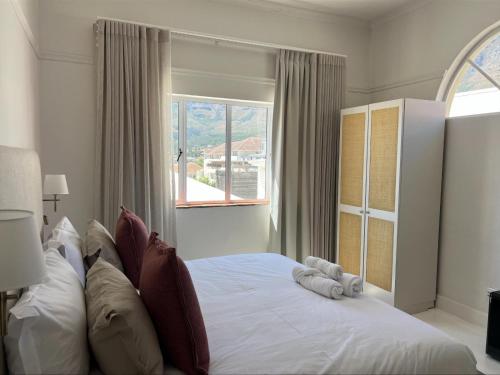 a bedroom with a white bed with a window at Nomad City Suites in Cape Town