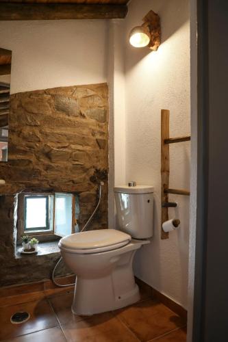 a bathroom with a toilet and a stone wall at Casa da Moleira in Chaveirinha
