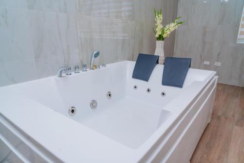 a bathroom with a white tub with a vase of flowers at Royale Jazz Hotel in Kingston
