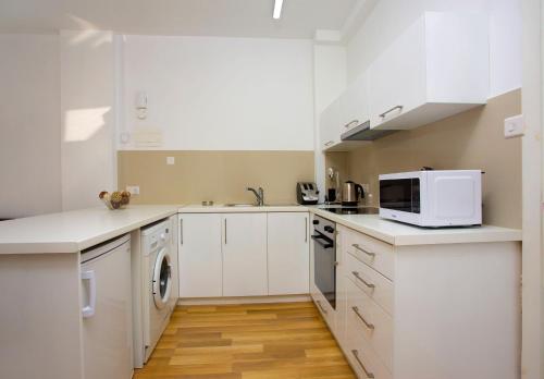 a kitchen with white cabinets and a microwave at SeaBreeze City Center Flats by TrulyCyprus in Limassol