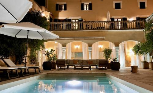 a swimming pool with an umbrella next to a building at Villa Nekazabal in Sa Pobla