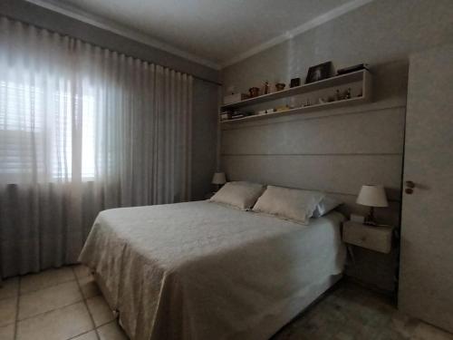 a bedroom with a large bed and a window at Confortável e bem localizada, com 2 quartos e garagem in São João da Boa Vista
