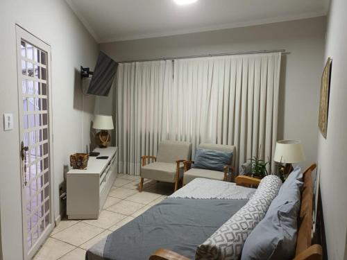 a bedroom with a bed and a living room at Confortável e bem localizada, com 2 quartos e garagem in São João da Boa Vista