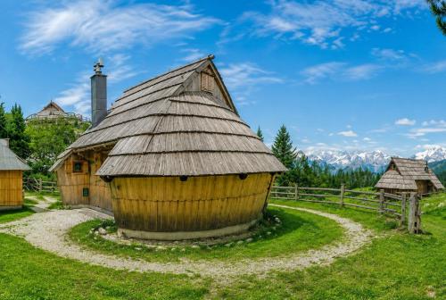 a wooden hut with a roof on a grass field at Chalet Lepenatka with Sauna - I feel Alps in Stahovica
