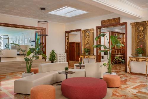 ein Wohnzimmer mit Sofa, Sesseln und Pflanzen in der Unterkunft Hotel Cap Roig & Spa by Brava Hoteles in Platja  d'Aro