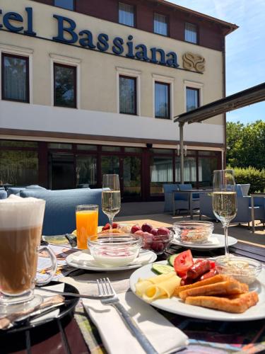 a table with plates of food and glasses of wine at Bassiana Hotel és Étterem in Sárvár