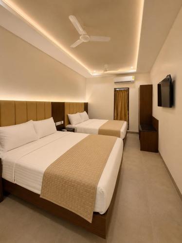 a hotel room with two beds and a flat screen tv at Arthana Grand Inn in Udumalaippettai
