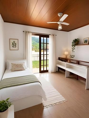 a bedroom with a bed and a ceiling fan at Chalé Charmoso na Serra de Penedo in Penedo