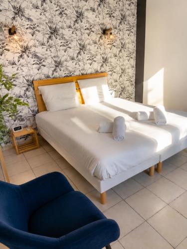 a bedroom with two beds and a blue chair at La Tropicale - Terrasse Privée Entre Lac & Océan- C' LA VIEconciergerie in Soustons