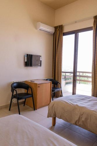 a hotel room with two beds and a desk and a window at Saint Paul Guesthouse in Zahlé