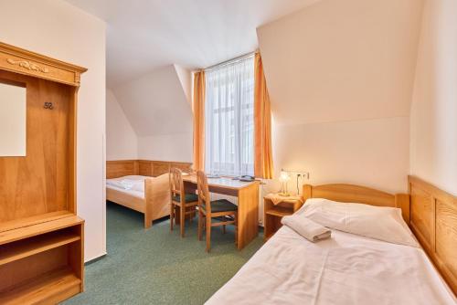 a room with two beds and a desk and a window at Hotel Krakonoš in Trutnov