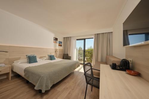 a hotel room with a large bed and a window at Hotel Playa Mondrago in Portopetro