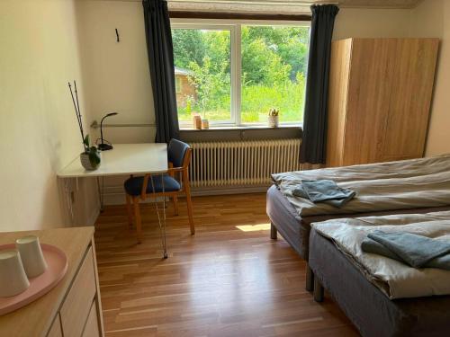 ein Schlafzimmer mit Bett, Schreibtisch und Fenster in der Unterkunft Room for rent Landsbyen in Videbæk