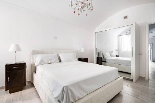 a white bedroom with a large bed and a mirror at Da Marilena in Sorso