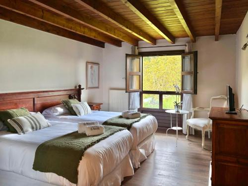 a bedroom with two beds and a tv and a window at El Balcón Del Profesor in Cereceda
