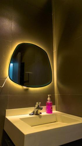 a bathroom sink with a mirror and a pink soap at Reign Residence in Port Harcourt