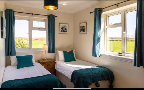 a bedroom with two beds with blue curtains and windows at Deighton Lodge in York