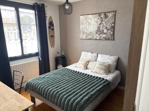 a bedroom with a bed with a green blanket on it at Chez Emma in Niort