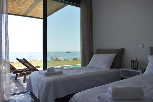 a bedroom with two beds and a view of the ocean at Μαυρόλιθος in Karistos