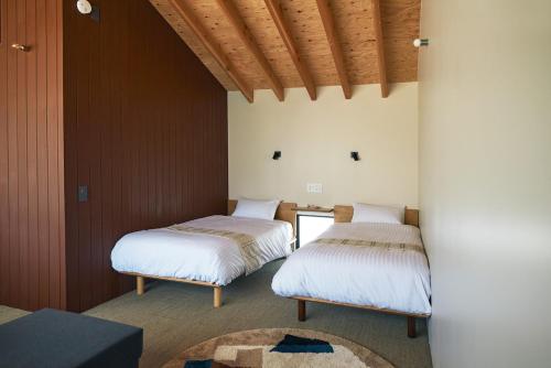 two beds in a room with wooden walls at SUISUI Hakushu Hotel in Shirasu