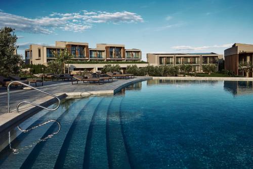 a large pool of blue water in front of buildings at Zelia Halkidiki, part of Destination by Hyatt - Adults Only in Nea Potidaea