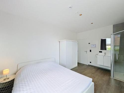 a white bedroom with a white bed and a glass wall at Stellaross - Koksijde in Koksijde