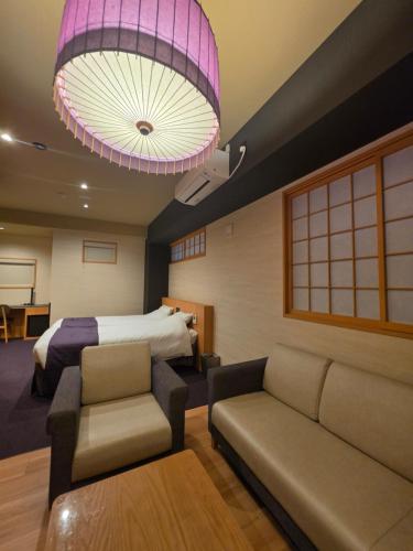 a bedroom with a bed and a couch and a lamp at Hotel Matsunoi Shurin in Tokyo