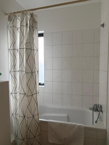 a bathroom with a tub and a shower curtain at Bifröst Apartments in Bifrost