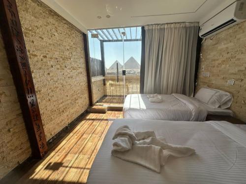 two beds in a room with a large window at Vida Pyramids Inn in Cairo