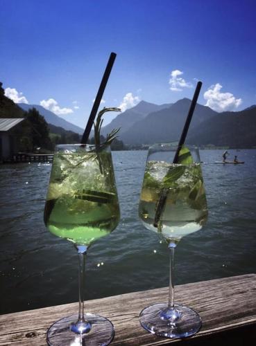 two wine glasses sitting on a table next to the water at Fewo TG in Schliersee