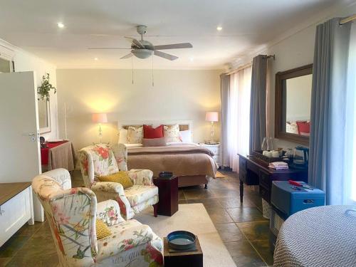 a bedroom with a bed and a couch and chairs at Connemara Farm in Himeville