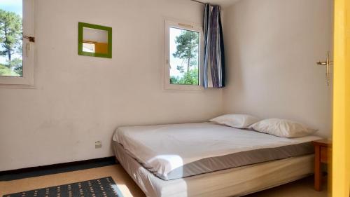 a bed in a room with two windows at Résidence Mes Amours d'Enfants - Les Villas du Lac in Soustons