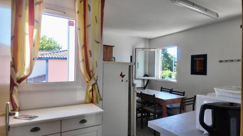 a kitchen and dining room with a table and a refrigerator at Résidence Mes Amours d'Enfants - Les Villas du Lac in Soustons