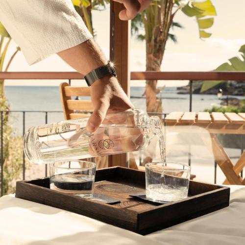 a person pouring a drink into two glasses on a table at Boutique Apartments Marsol Ibiza in Santa Eularia des Riu