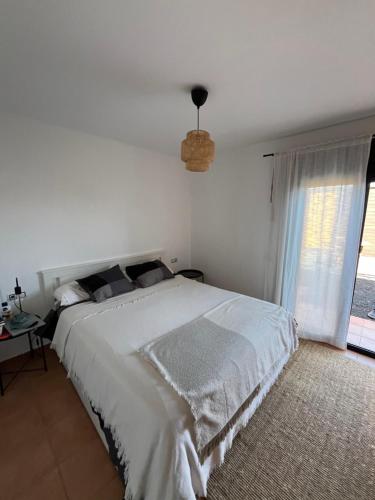 a white bedroom with a large bed and a window at Fuerte Wave House in Lajares