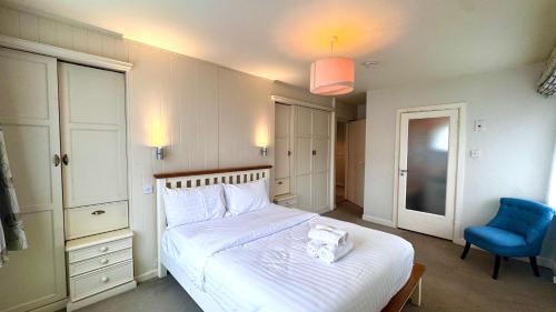 a bedroom with a white bed and a blue chair at The Lodge, Whitethorns, Myrtleville in Myrtleville