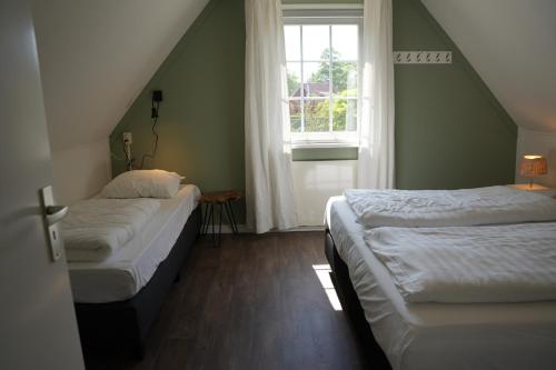 two beds in a room with a window at De Brittenburg 4-persoons, finse sauna, hottub, sunshower, grote zonnige omheinde tuin, wifi en huisdier vriendelijk in Lievelde