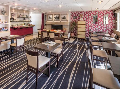 a restaurant with tables and chairs and a fireplace at Hôtel La Résidence in Roscoff