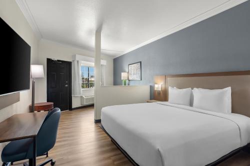 a bedroom with a large white bed and a desk and a tv at Hyatt Select Galveston Beachfront in Galveston