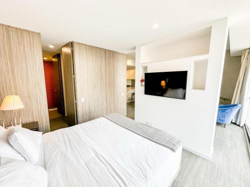 a bedroom with a white bed and a flat screen tv at Distrito prime 1-303 in Bogotá