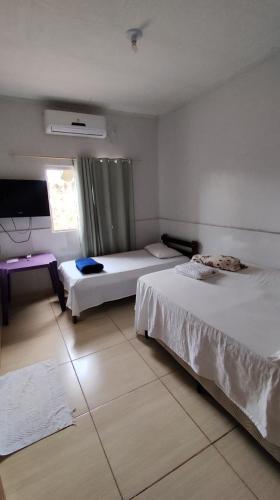 a hotel room with two beds and a television at Hotel Gramados in Porangatu