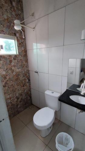a bathroom with a white toilet and a sink at Hotel Gramados in Porangatu