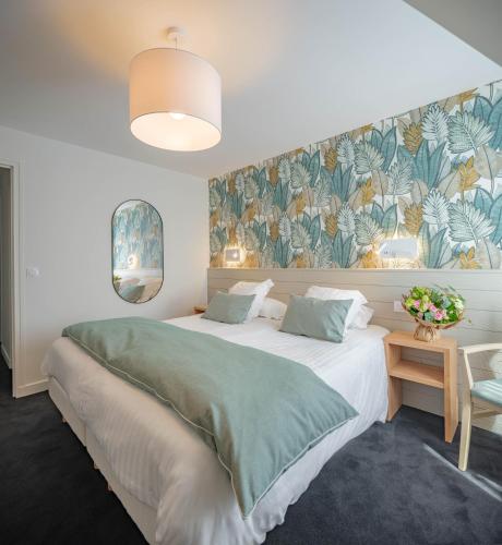 a bedroom with a large bed with a green blanket at Hôtel La Résidence in Roscoff
