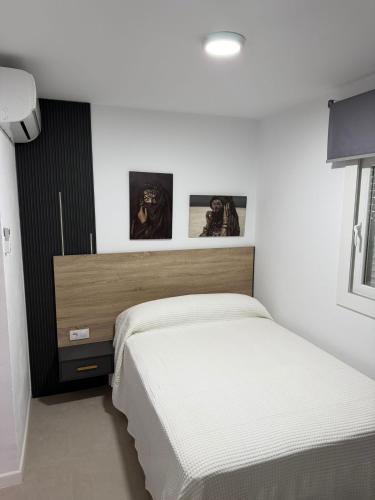 a white bedroom with a bed and a window at Atico casa la via in Sanlúcar de Barrameda