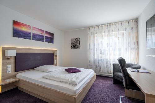 a bedroom with a bed and a desk and a table and a chair at Hotel Villa Sulmana in Neckarsulm