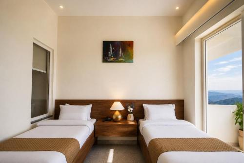 two beds in a room with a window at Anuttara Retreat in Narendranagar